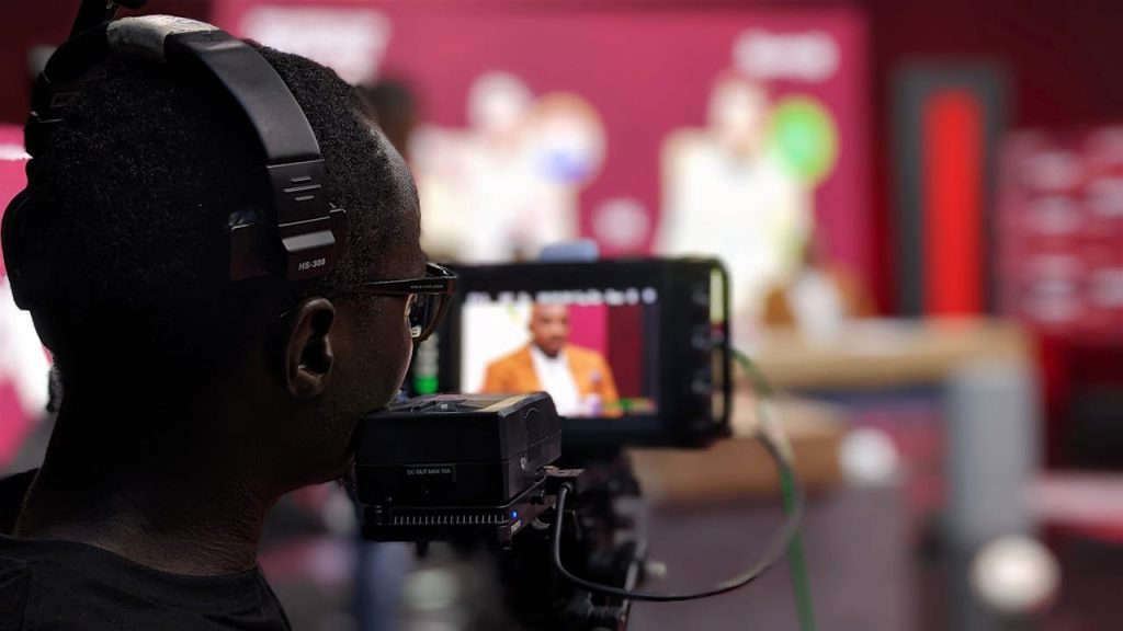 Close-up of a cameraman with headphones filming a program in a studio setting.
